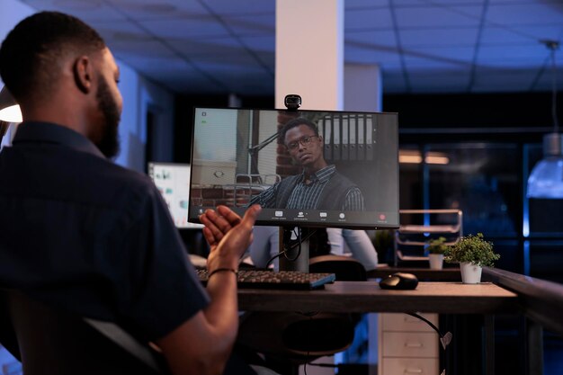 Un employé de l'entreprise rencontre un homme lors d'une téléconférence à distance, utilisant une webcam et un ordinateur pour discuter sur Internet. Appel en visioconférence en ligne pour le télétravail et les télécommunications.