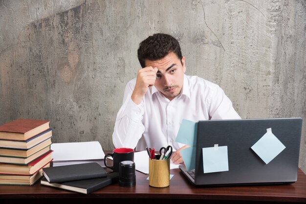 Employé fatigué regardant un ordinateur portable au bureau.