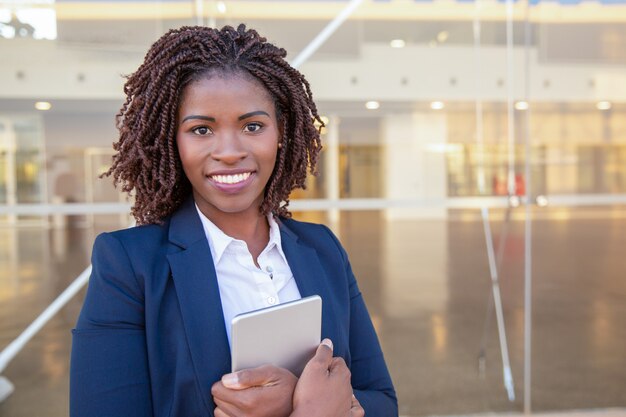 Employé heureux avec tablette posant près d'un immeuble de bureaux