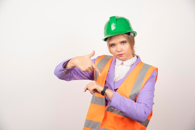 Employé industriel féminin pointant le temps sur fond blanc. Photo de haute qualité