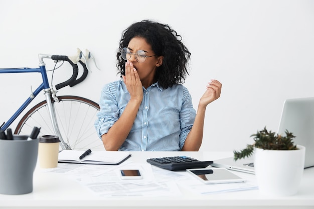 Photo gratuite employé de jeune femme à la peau foncée fatiguée en lunettes couvrant la bouche ouverte