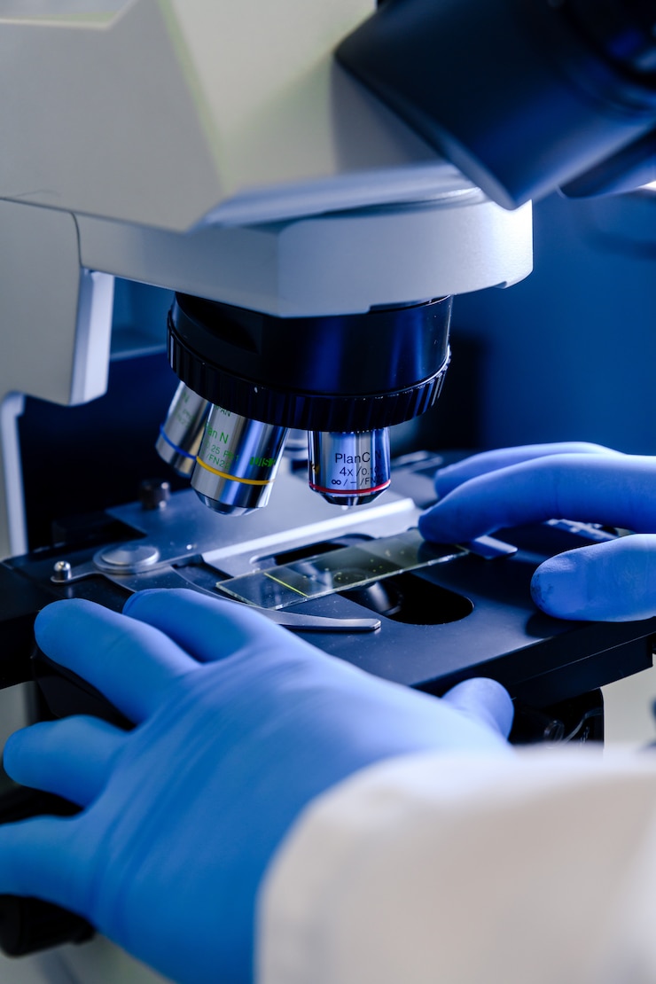Photo gratuit un employé de laboratoire travaillant avec un microscope moderne lors d'une recherche sur les coronavirus