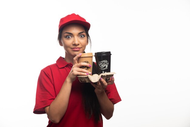 Employé de livraison femme au bonnet rouge tenant deux tasses de café