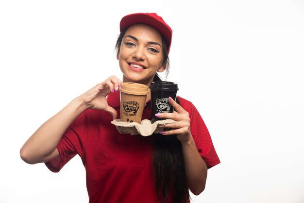 Employé de livraison femme au bonnet rouge tenant deux tasses de café