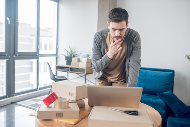 Employé de magasin Internet concentré regardant fixement l'écran de son ordinateur portable