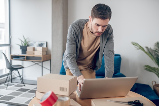 Employé de magasin en ligne concentré travaillant sur l'ordinateur portable