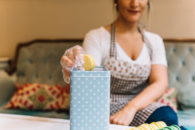 Photo gratuite employé de magasin préparant une boîte à macarons