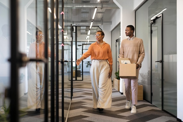 Photo gratuite employé masculin explorant son nouvel emplacement de travail de bureau tout en portant une boîte d'effets personnels