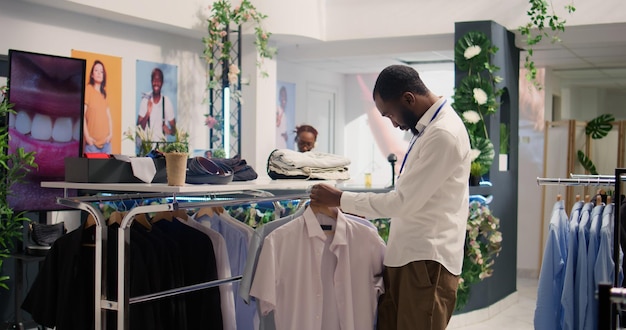 Photo gratuite l'employé met les vêtements sur des portants