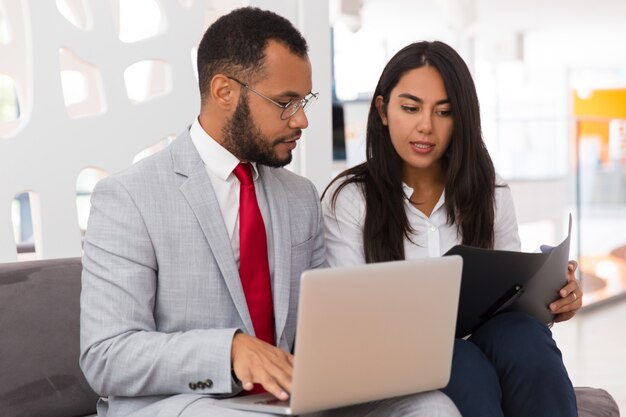 Employé sérieux consultant un collègue et montrant des documents