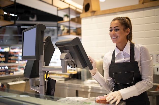 Employé de supermarché mesurant et vendant de la viande au client