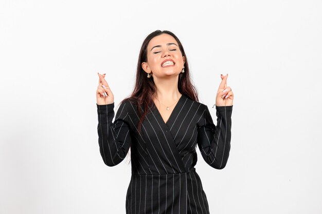 Employée de bureau en costume noir strict croisant ses doigts sur blanc