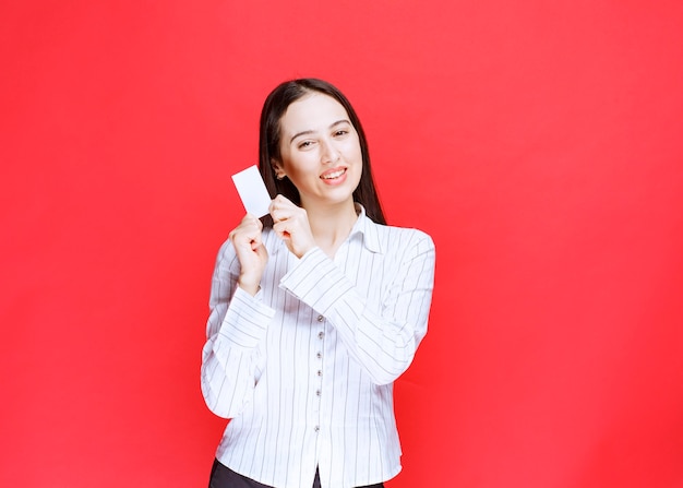 Employée de bureau montrant la carte de visite en souriant.