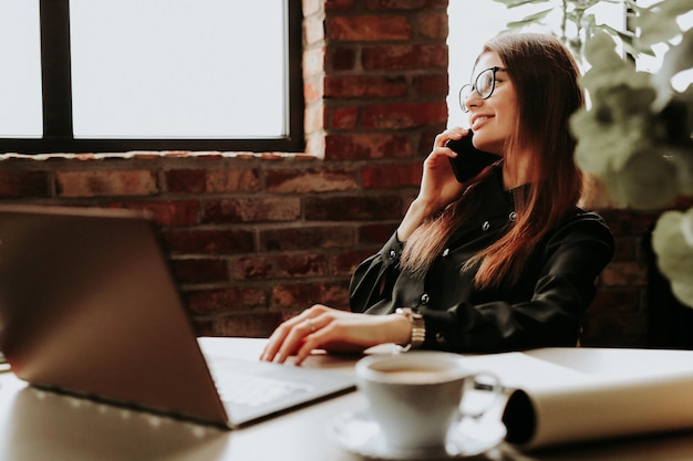 Employée travaillant au bureau à l'aide d'un téléphone et d'un ordinateur