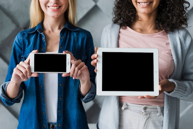 Photo gratuite employées de bureau ethniques montrant des écrans de gadgets