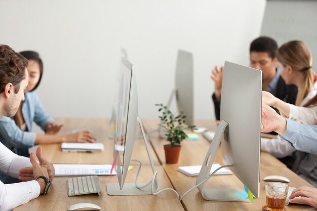 Employés de bureau travaillant sur des ordinateurs en coworking, bureau avec des moniteurs