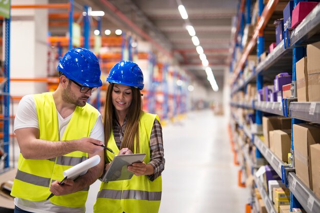 Les employés des entrepôts vérifient les stocks et se consultent sur l'organisation et la distribution des marchandises