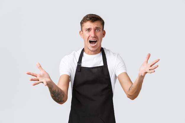 Photo gratuite employés, épiceries et concept de café. barista choqué face au désastre, à court de glace en été, panique et criant anxieux, écarte les mains sur le côté, explique le problème