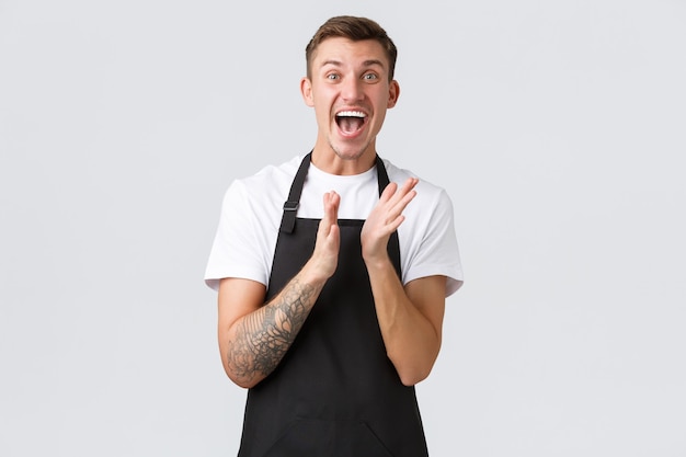 Employés, épiceries et concept de café. Heureux barista impressionné et excité en tablier noir applaudir pour une masterclass sur la préparation du café, applaudissements sur fond blanc