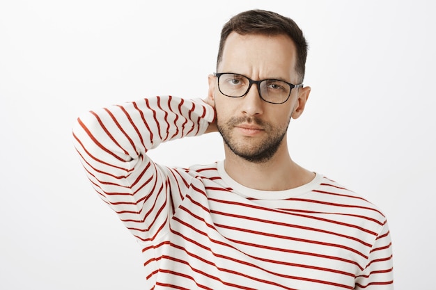 Photo gratuite employeur masculin adulte fatigué et déçu dans des lunettes noires, touchant l'arrière de la tête et fronçant les sourcils, à la concentration