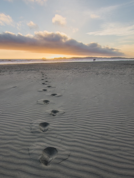 Empreintes de pieds dans le sable gris