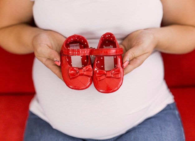 Enceinte Femme Tenant Des Chaussures Rouges