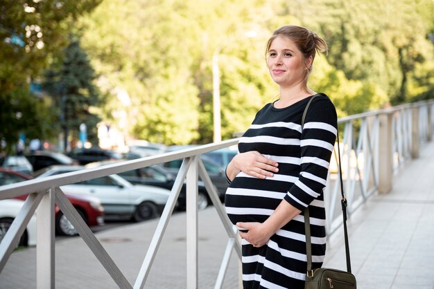 Enceinte femme tenant son ventre à l'extérieur