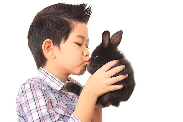 Enfant asiatique jouant avec joli bébé lapin isolé sur blanc