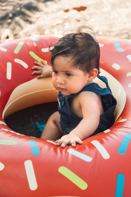 Photo gratuite enfant en bas âge assis sur le sable en cercle de natation