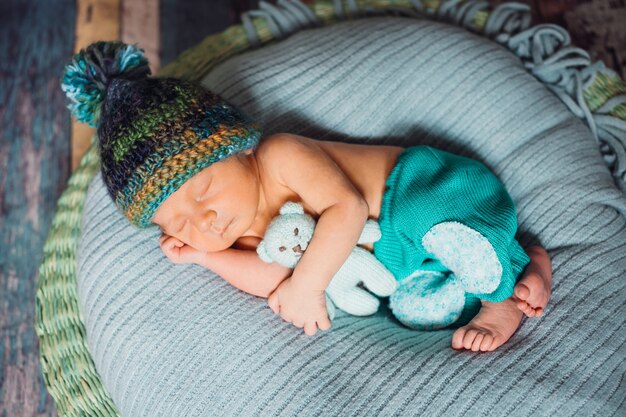 Enfant en bonnet tricoté dort sur grand coussin bleu