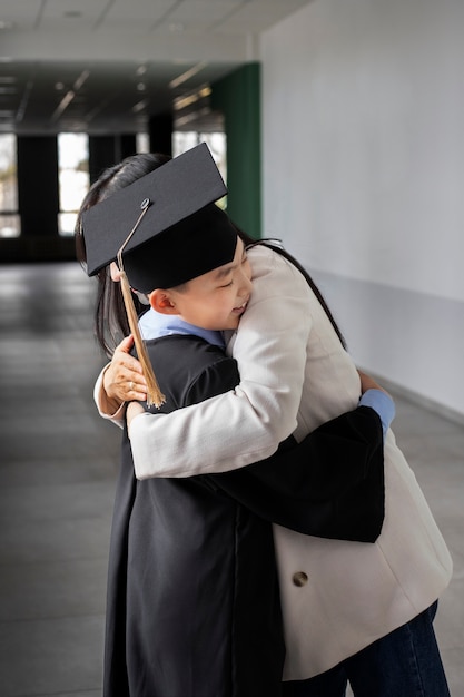 Enfant célébrant l'obtention du diplôme de maternelle avec un parent