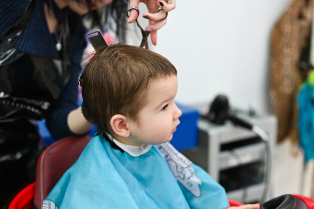 Un Enfant Chez Le Coiffeur La Premiere Coupe De Cheveux De L Enfant Chez Le Coiffeur Bebe Coupe De Cheveux Enfant En Bas Age Photo Premium