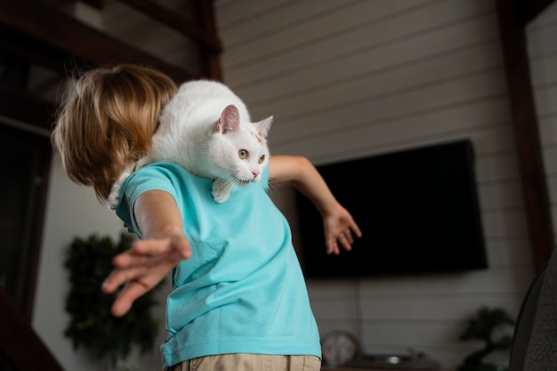 Photo gratuite enfant de coup moyen jouant avec un chat