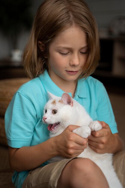 Enfant de coup moyen tenant un chat adorable