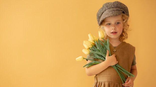 Enfant de coup moyen tenant des fleurs