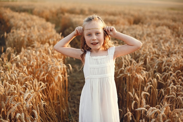Enfant dans un champ de blé d'été. Petite fille dans une jolie robe blanche.