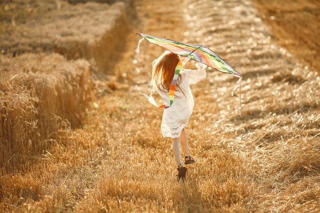 Enfant dans un champ d'été. Petite fille dans une jolie robe blanche. Enfant avec un KITE.