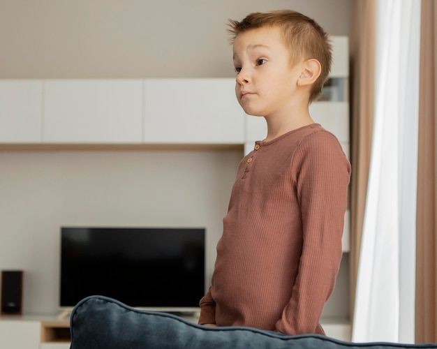 Photo gratuite enfant debout sur le canapé et regardant ailleurs