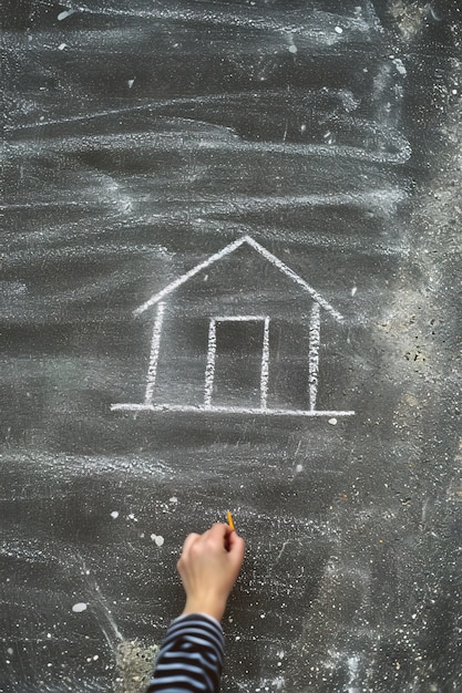 Photo gratuite un enfant dessine une maison avec de la craie sur la route.