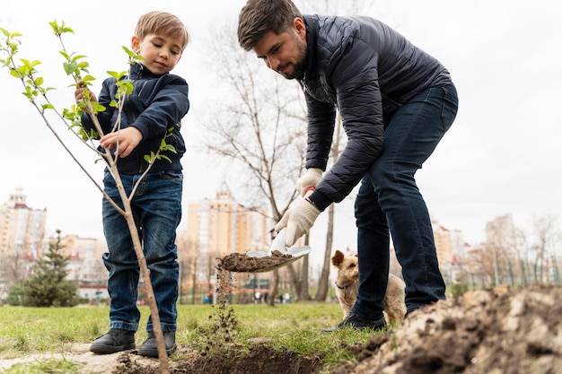 Photo gratuite enfant essayant de planter un arbre à l'extérieur