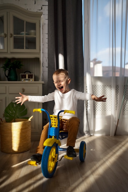 Photo gratuite enfant excité plein coup sur tricycle