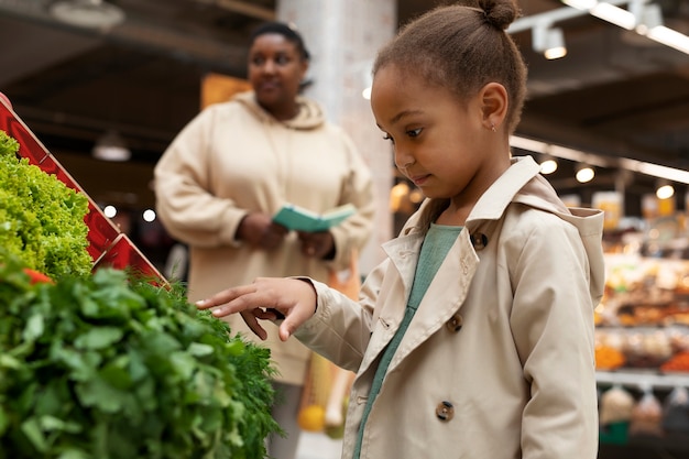 Enfant et femme de coup moyen au marché