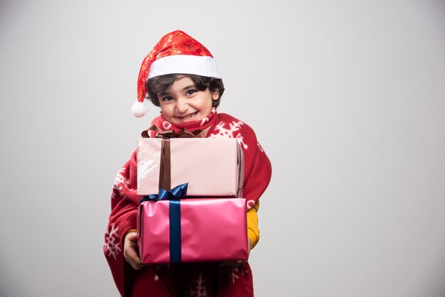 Enfant gai dans l'uniforme de Santa tenant des cadeaux de Noël