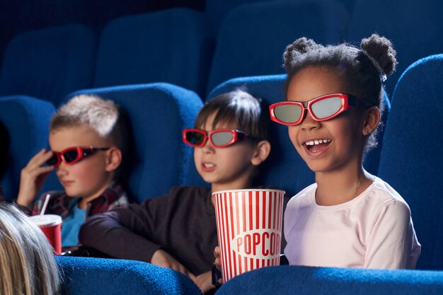 Enfant heureux dans des lunettes 3d en regardant un film comique au cinéma