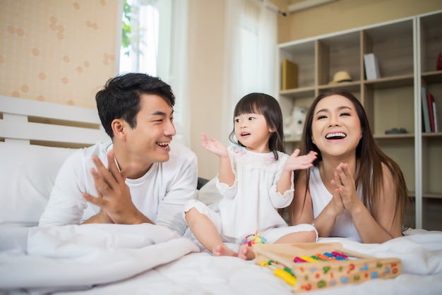 Enfant heureux avec les parents jouant dans le lit à la maison