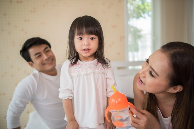 Enfant heureux avec les parents jouant dans le lit à la maison