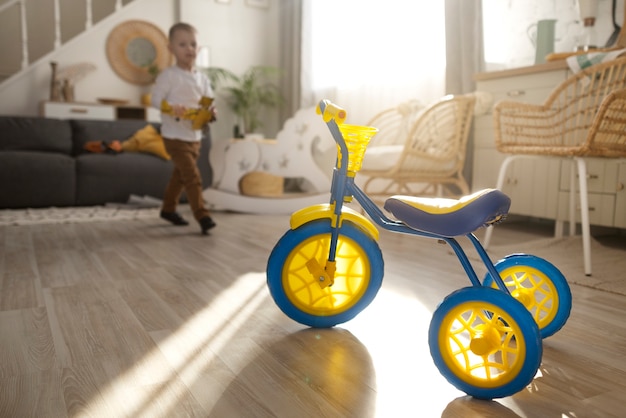 Enfant heureux plein coup avec tricycle à la maison