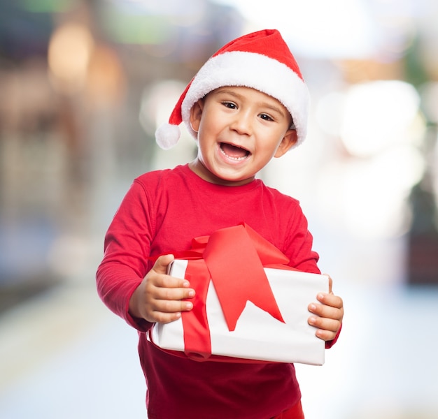 enfant heureux tenant son cadeau avec arrière-plan flou