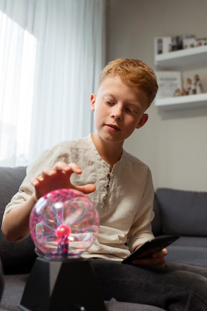 Photo gratuite enfant interagissant avec une boule de plasma