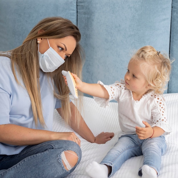 Enfant jouant avec un thermomètre à côté de maman